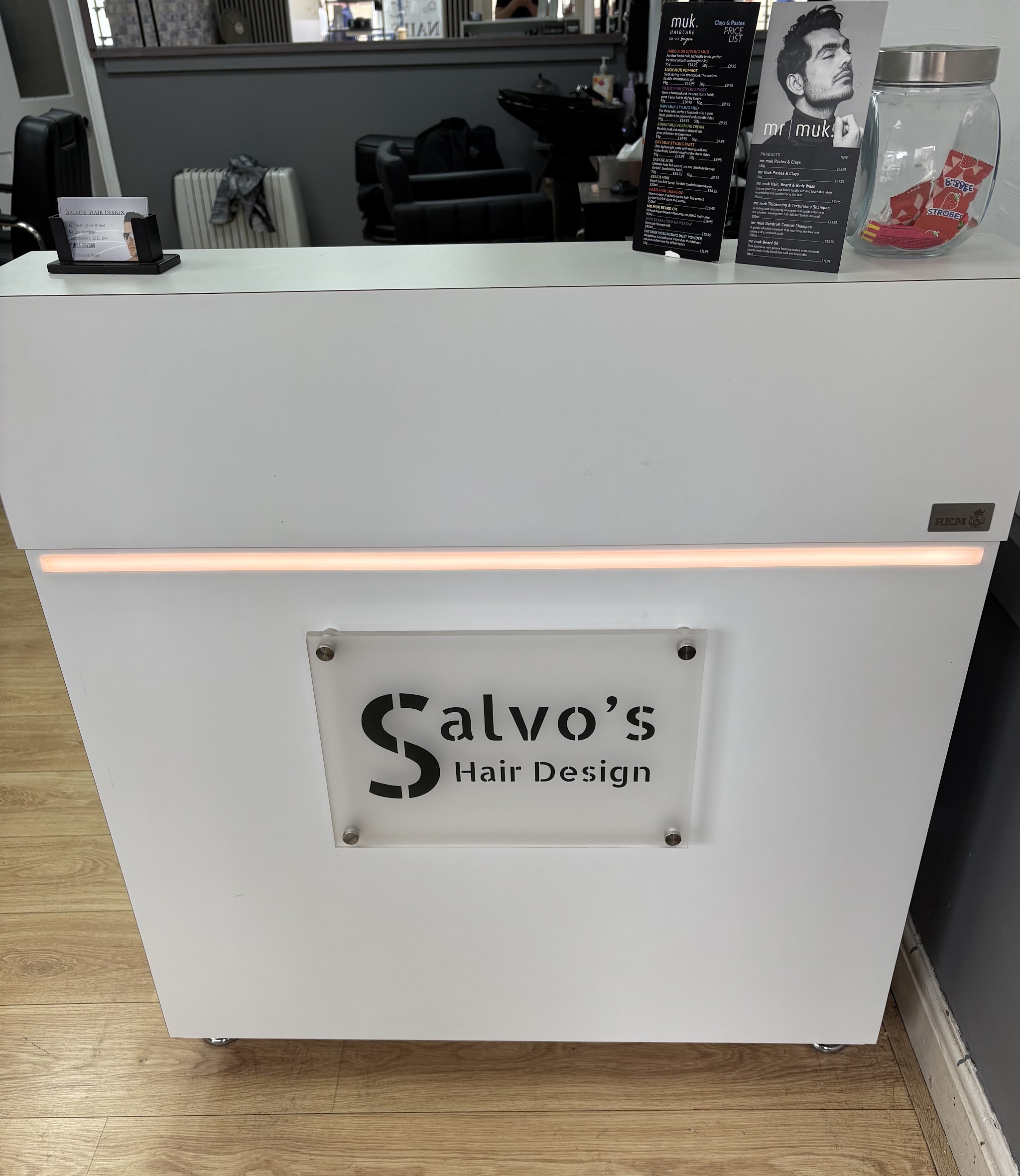 The white reception desk with the Salvo's Hair Design sign