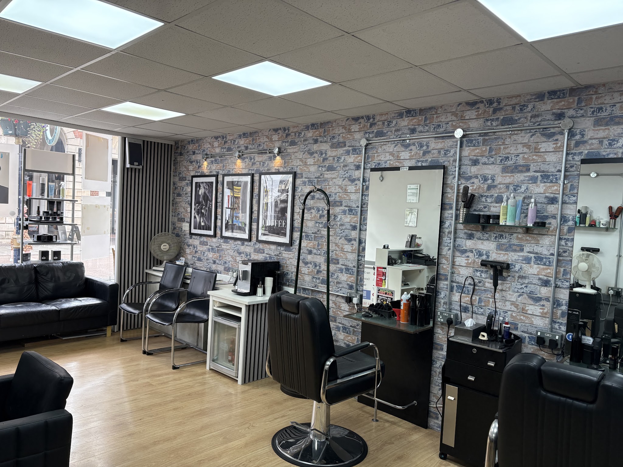 Inside Salvo's: brick feature wall with framed prints, black barber chairs and styling stations